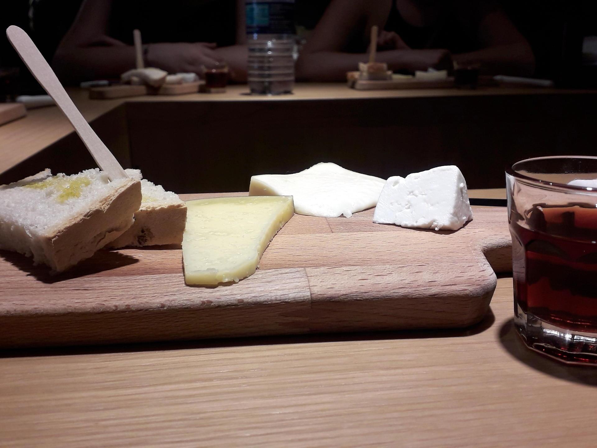 A rustic cutting board with cheese, bread, and port wine, perfect for a Braga food tour experience.