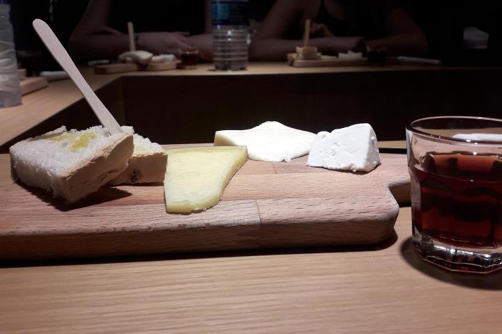 A rustic cutting board with cheese, bread, and port wine, perfect for a Braga food tour experience.