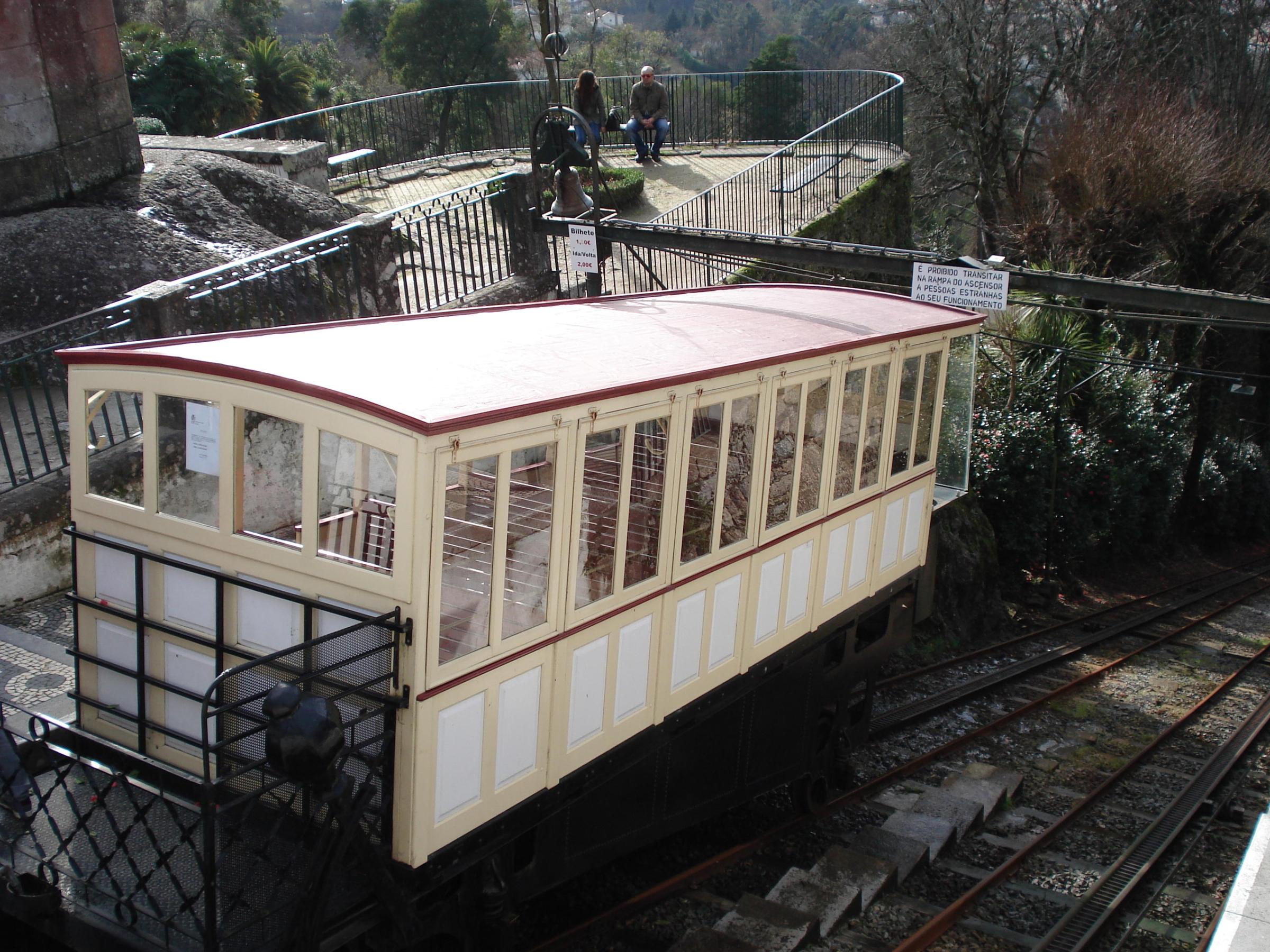 Funicular on the Braga tour, passing over lush greenery and historic architecture at Bom Jesus Sanctuary.