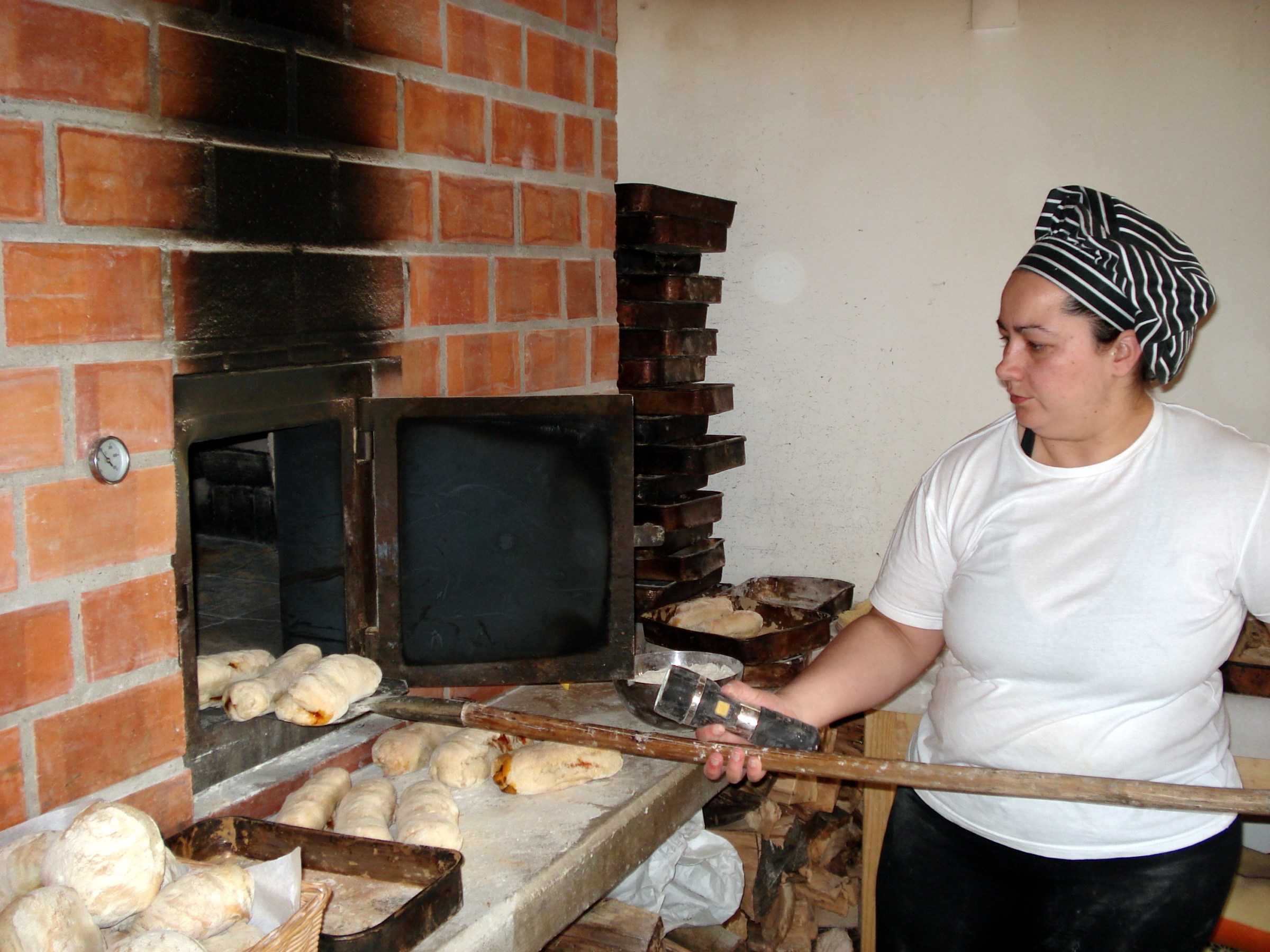 a woman cooking chorizo bread in the wood oven