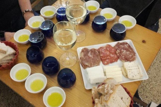 A table filled with plates of Portuguese wine, olive oil, bread, chorizo, ham, and cheeses, ready for a delicious tasting.