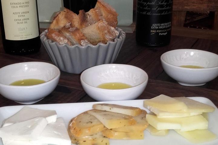 A beautifully set table showcasing plates of bread, chorizo, ham, cheeses, and Portuguese wine for an olive oil tasting.
