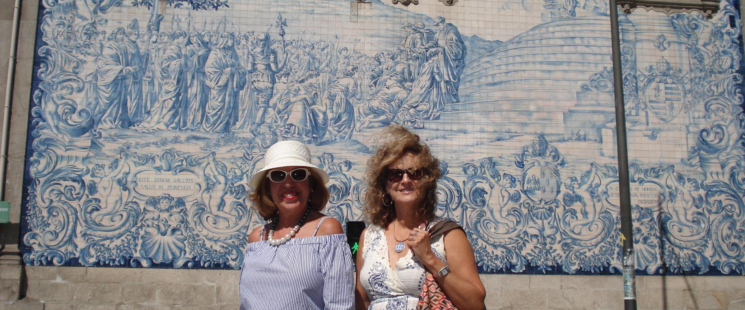 Two women pose in front of a beautiful building during their walking tour in Porto, smiling and enjoying the scenery.