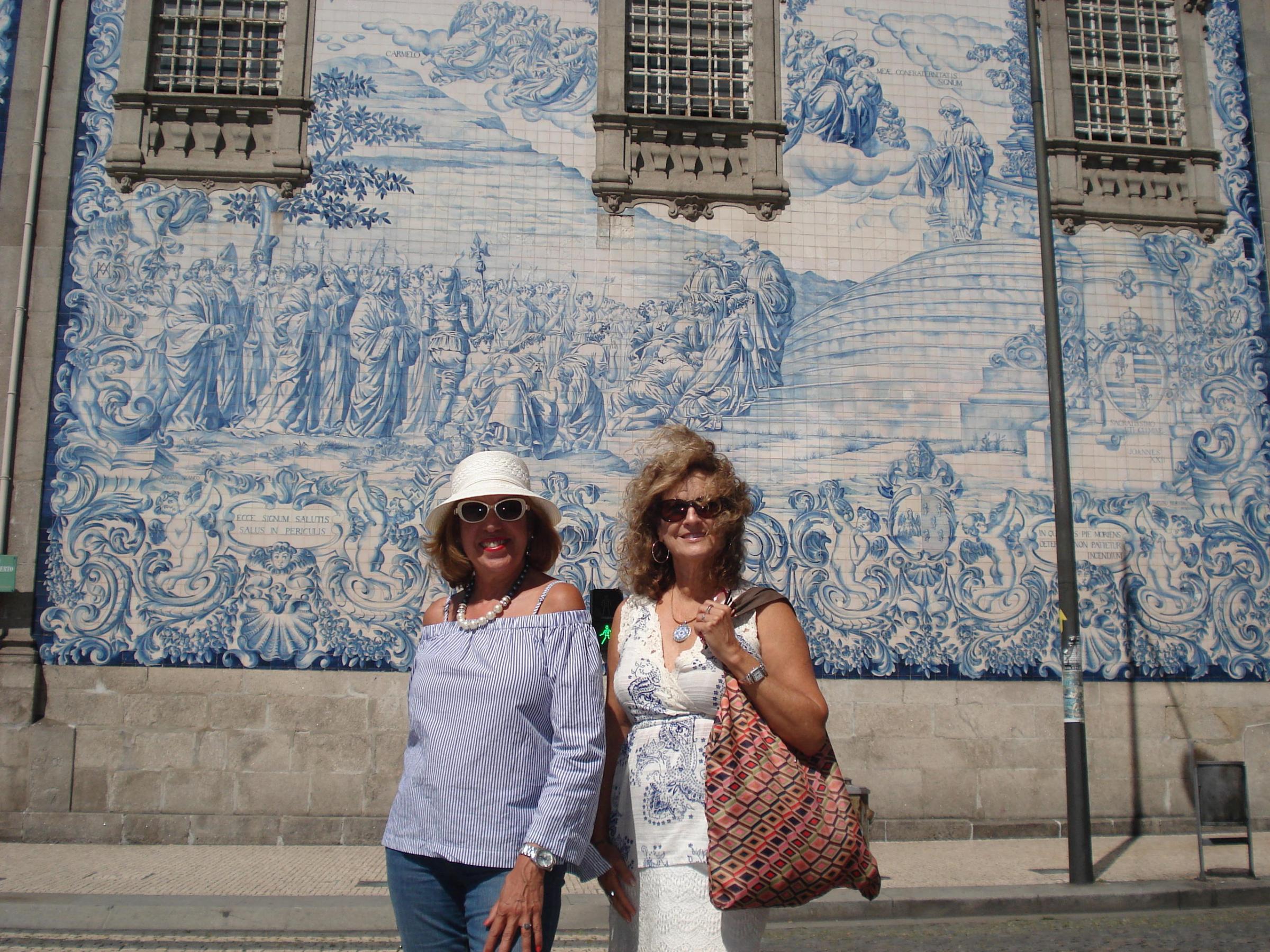 Two women pose in front of a beautiful building during their walking tour in Porto, smiling and enjoying the scenery.