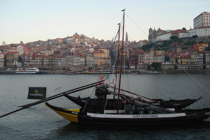 traditional rabelo boat featuring a large wooden mast navigates the scenic waters of Porto on a city walking tour.