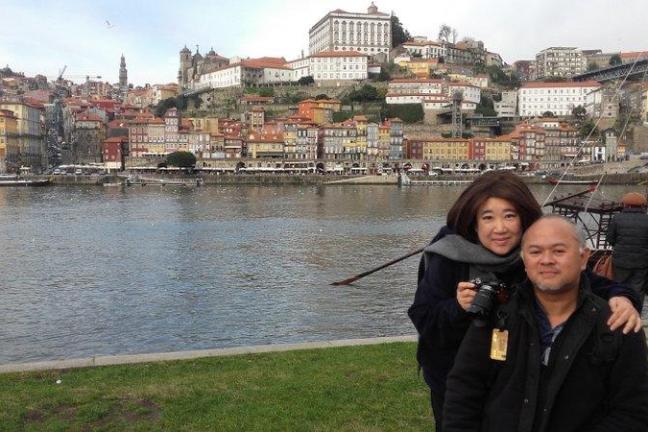 A couple stands smiling in front of a beautiful building, enjoying their Porto Walking Private Tour experience.