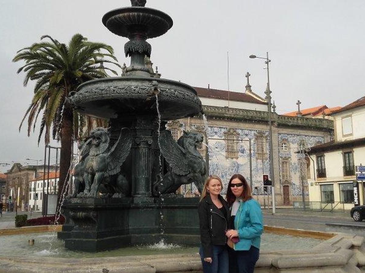 Women smile in front of a picturesque fountain, enjoying her Culinary Tour adventure in the heart of Portugal.
