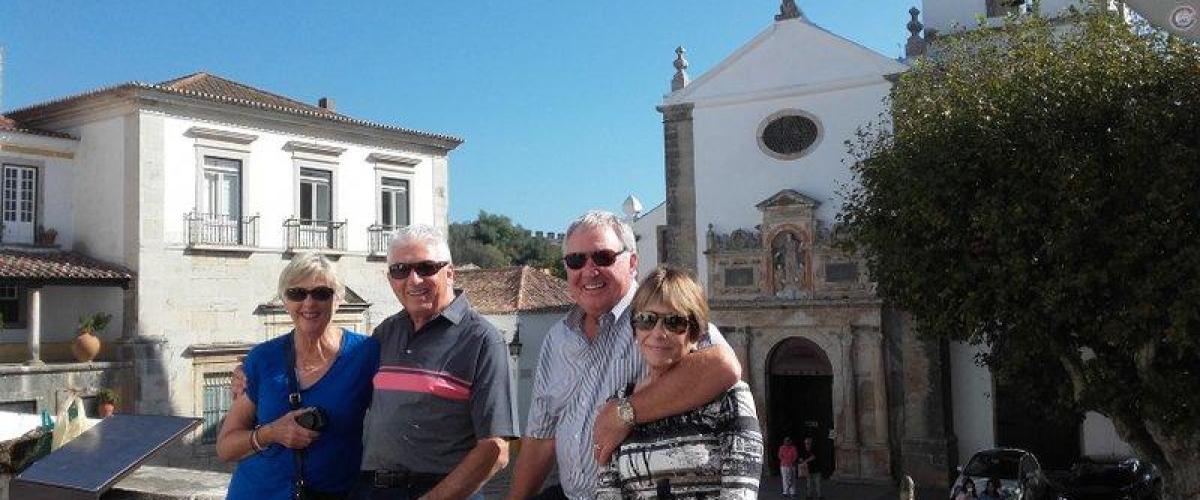 Four friends happily pose for a photo in front of a stunning church, enjoying their guided small group tour in Portugal.