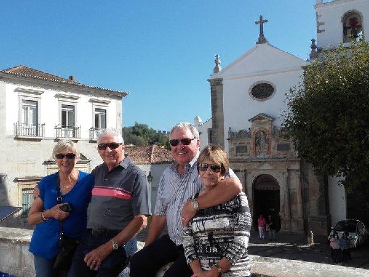 Four friends happily pose for a photo in front of a stunning church, enjoying their guided small group tour in Portugal.