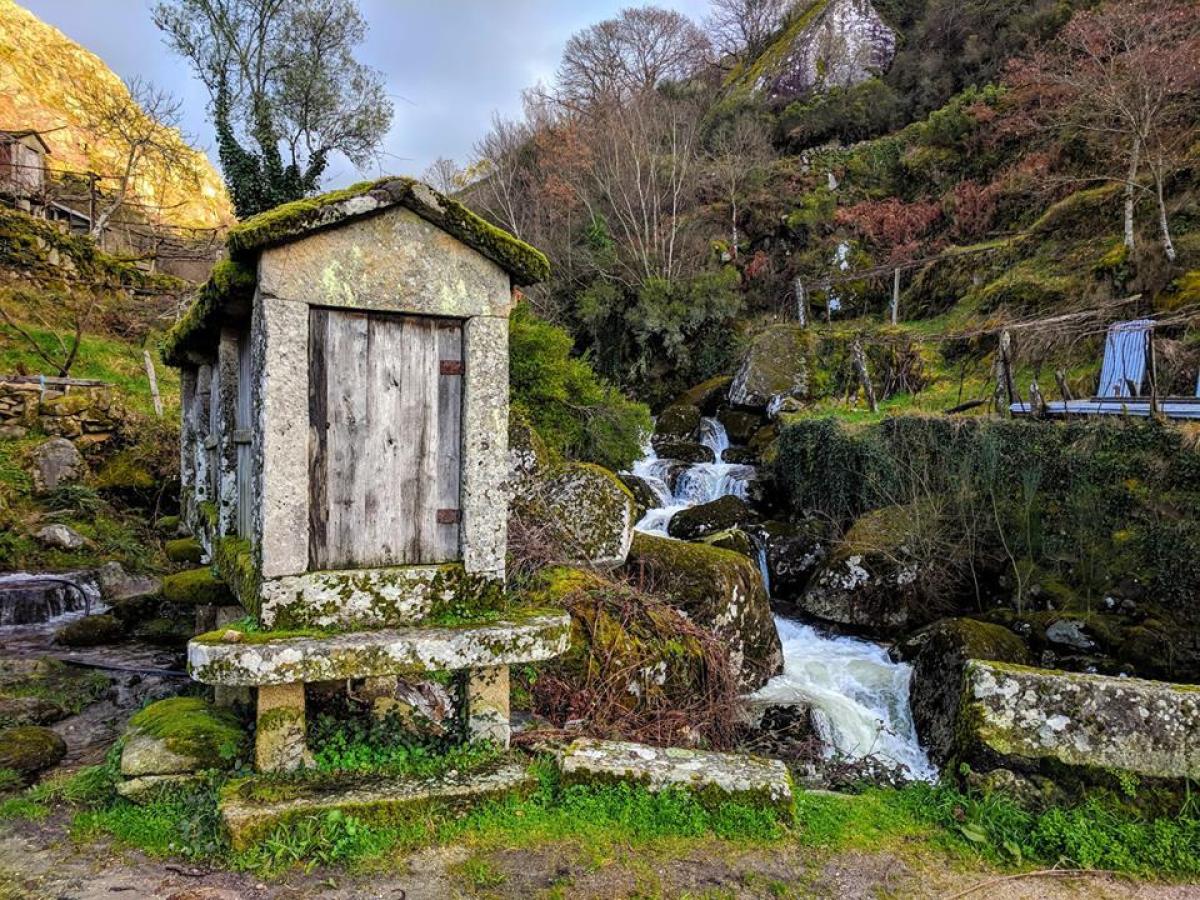 A charming outhouse nestled next to a cascading waterfall, inviting hikers on Sistelo Tours in Portugal to pause and enjoy.