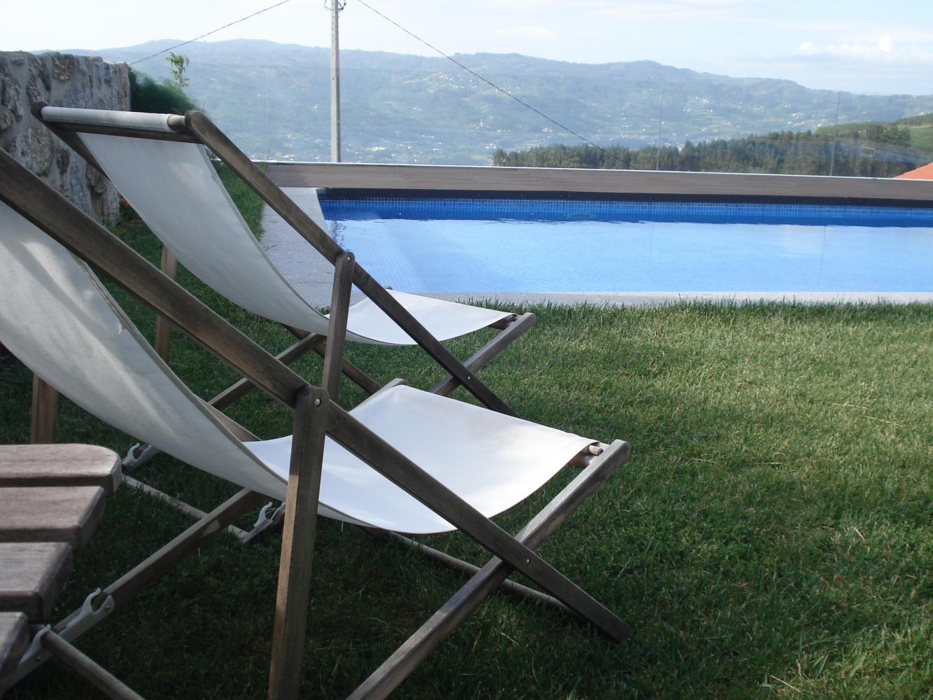 A picturesque hotel pool surrounded by grass, complete with an umbrella and chairs, ideal for enjoying culinary getaways.