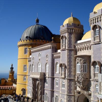 The impressive Pena Palace, characterized by its large size and multitude of windows, dominates the picturesque landscape.