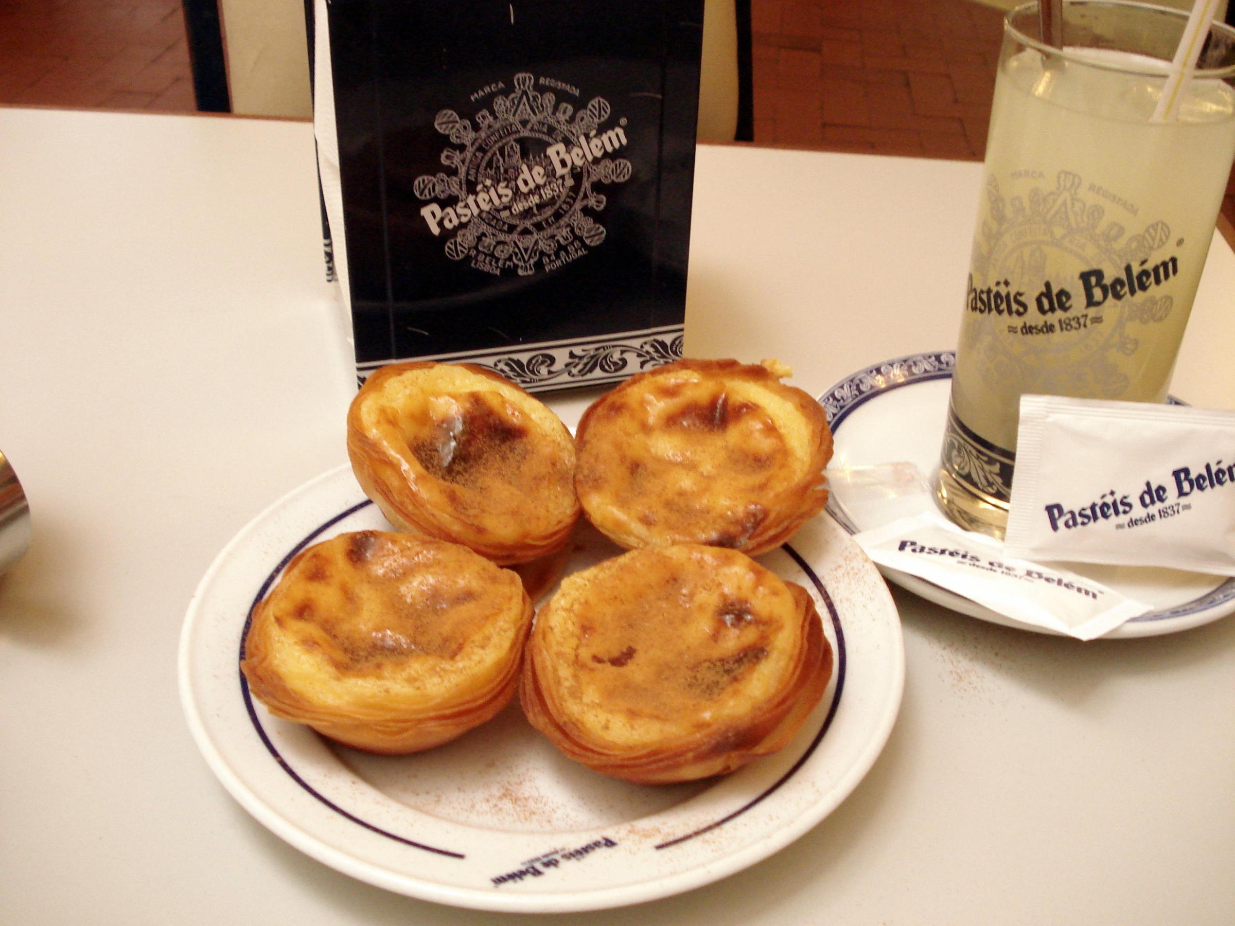 A tempting plate of custard tarts sits on a table in Lisbon, highlighting their rich, creamy texture and flaky pastry.