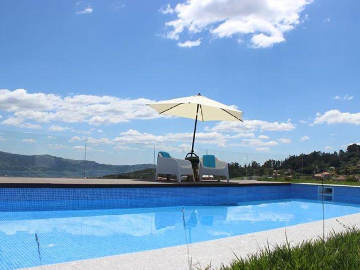 A tranquil hotel pool area with an umbrella and chairs on green grass, inviting guests to unwind during culinary vacations.