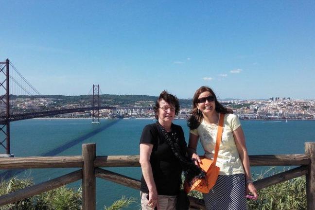 On the April 25 Bridge in Lisbon, two women enjoy the view of the tranquil water below, capturing a moment of connection.