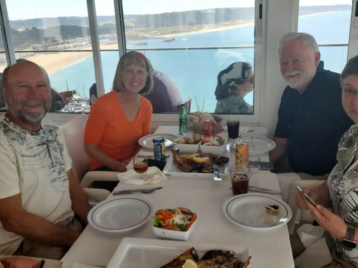 a group of people sitting at a table eating food during portugal tour