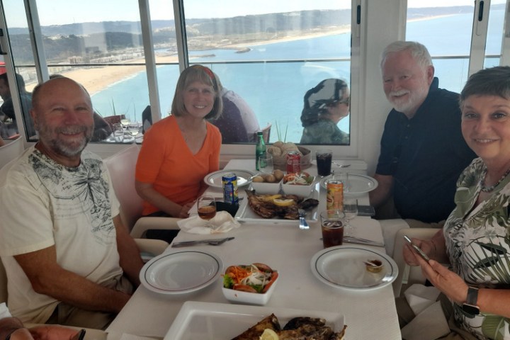 a group of people sitting at a table eating food during portugal tour