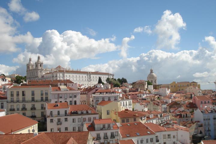 Bird's-eye view of Lisbon, featuring iconic rooftops and picturesque streets in warm sunlight.