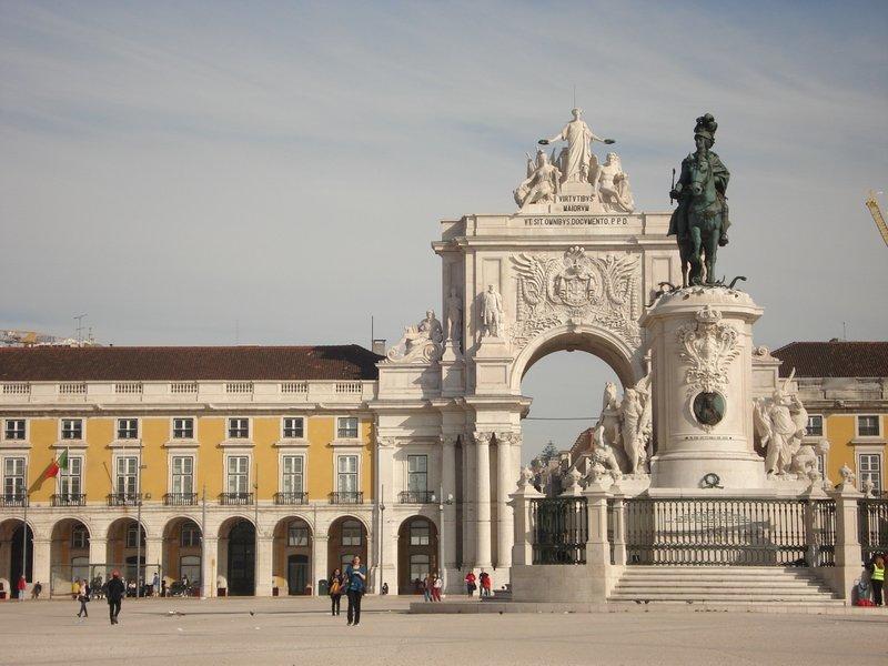 A large white building with a statue in front, located at Terreiro do Paço in Lisbon, showcasing stunning architecture.