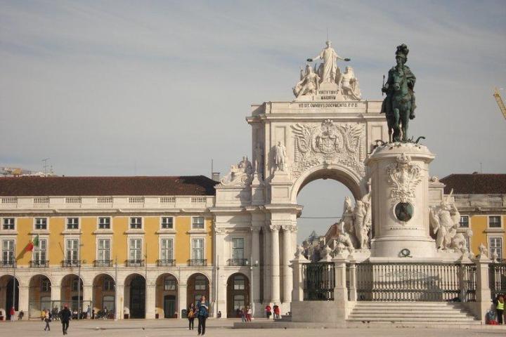 A large white building with a statue in front, located at Terreiro do Paço in Lisbon, showcasing stunning architecture.