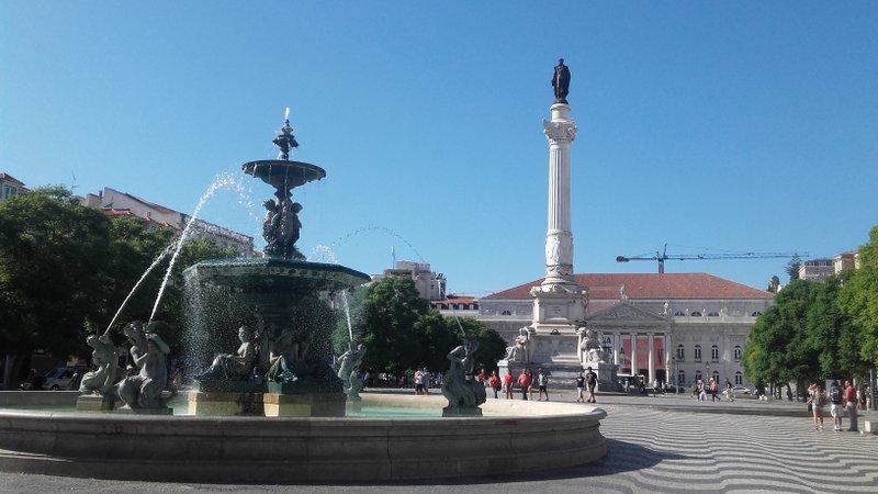 A beautiful fountain at Rossio Square, surrounded by vibrant city life in Lisbon, Portugal.