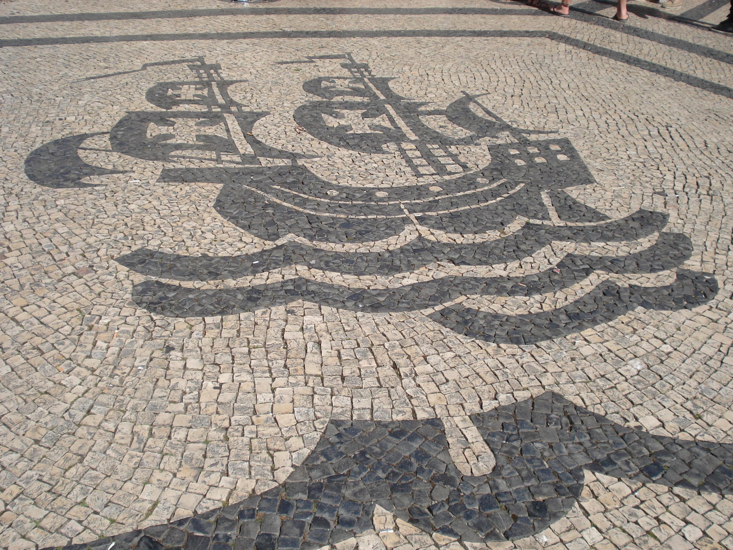 A traditional Portuguese sidewalk made of black and white limestone rocks arranged in intricate patterns.