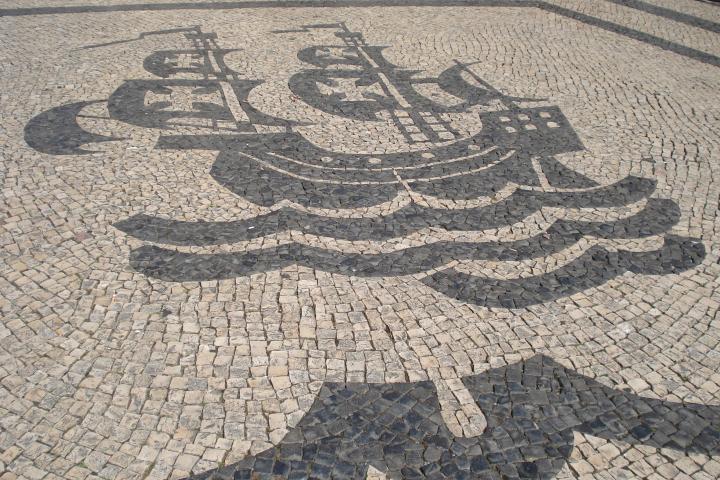 A traditional Portuguese sidewalk made of black and white limestone rocks arranged in intricate patterns.