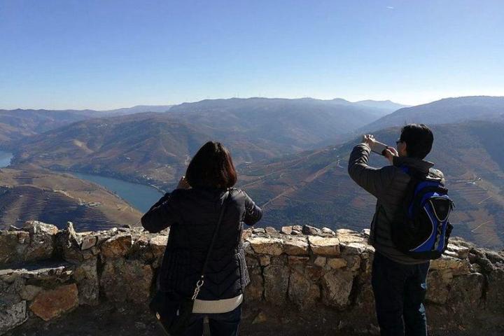 A couple captures a scenic view during their Douro Valley small-group tour, smiling with excitement in the beautiful landscape.