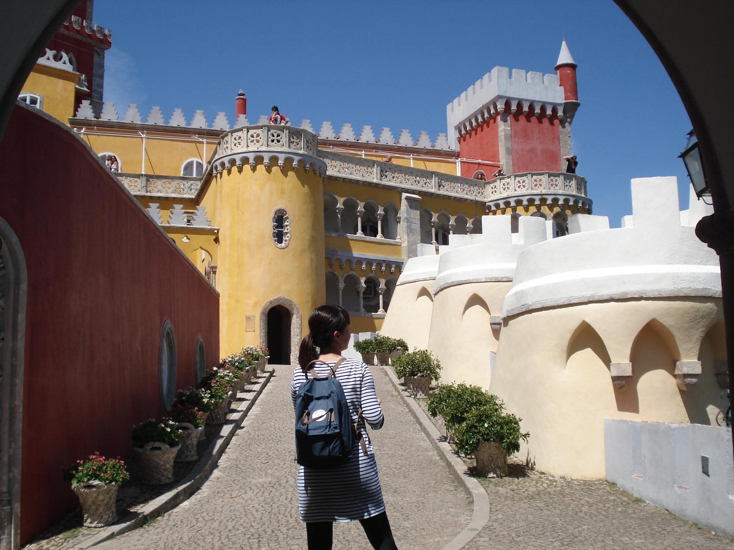 A woman with a backpack explores the vibrant Pena Palace in Sintra, embracing the spirit of solo travel.