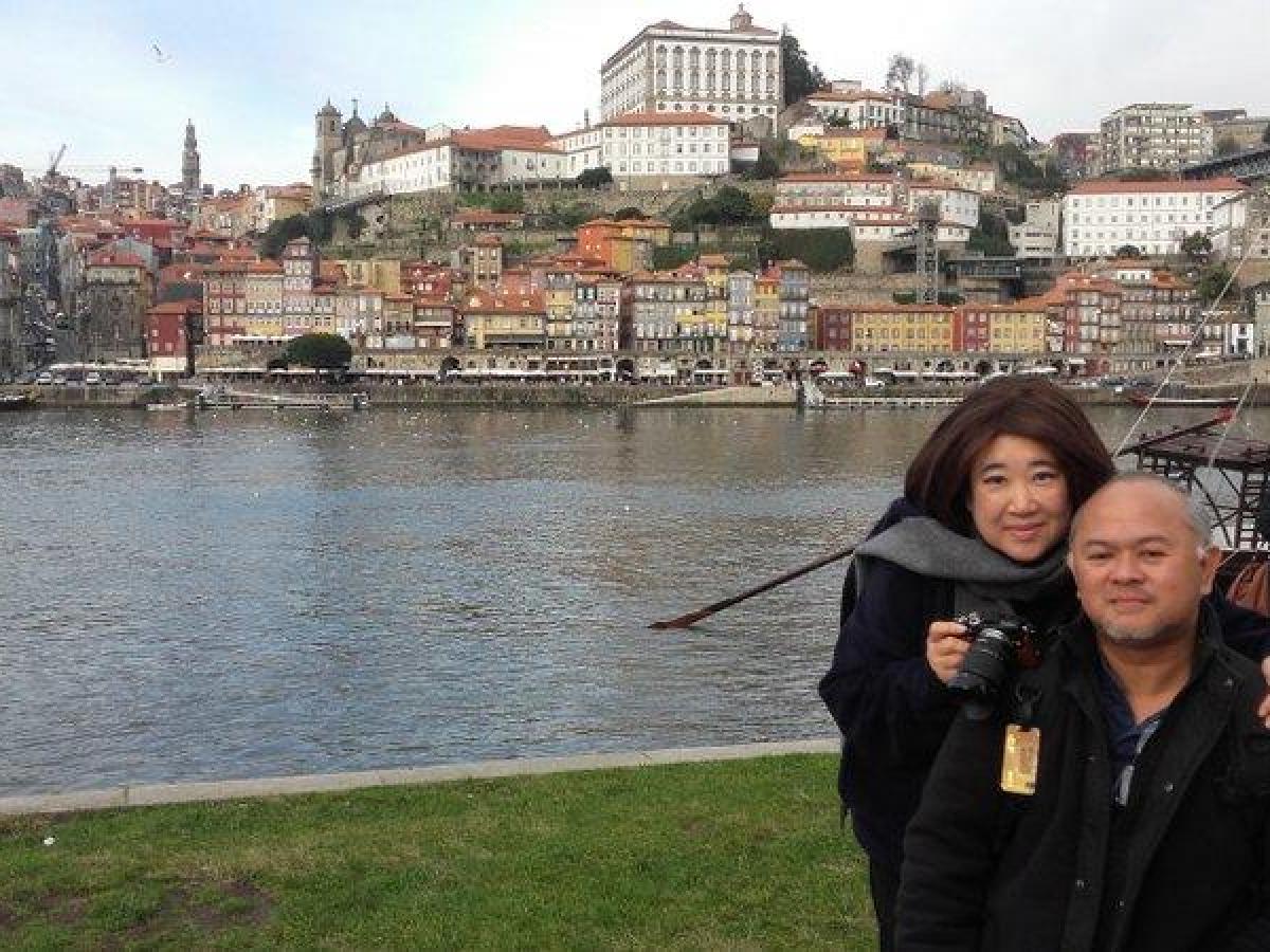 A man and woman pose together in front of a historic building during their Porto Walking Private Tour.