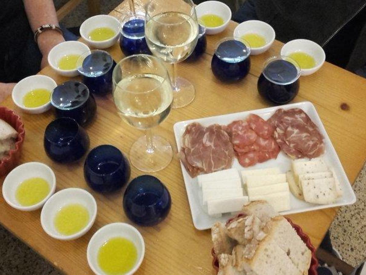 A beautifully arranged table featuring plates of olive tasting, Portuguese wine, bread, ham, chorizo, and assorted cheeses.