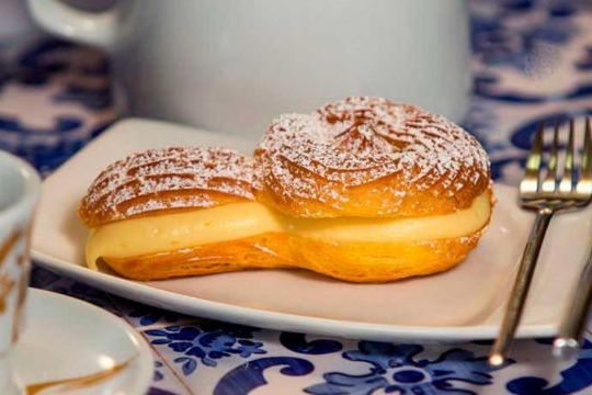 A white plate holds a tibia cake, showcasing delicious pastries from the Braga food tour experience.