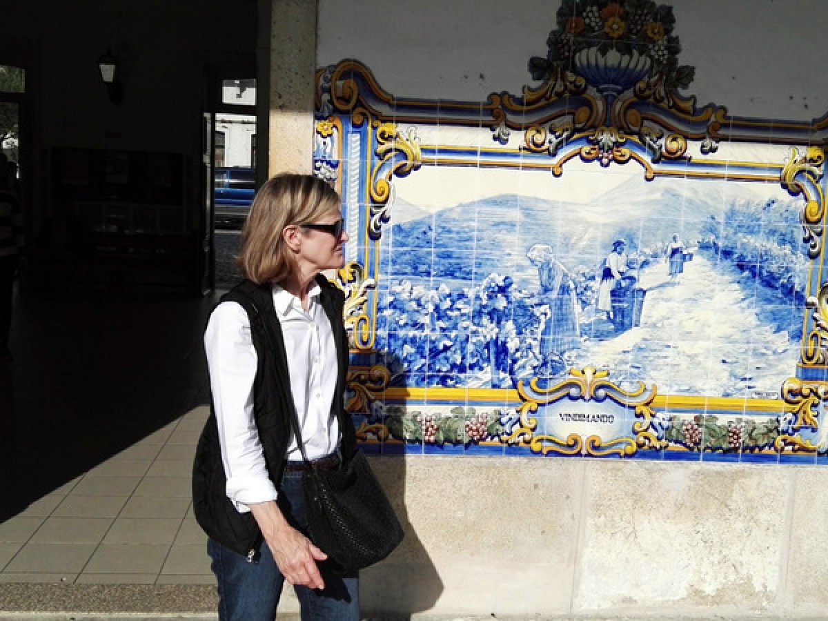 A woman poses gracefully in front of a stunning blue and white tile wall, capturing the essence of Douro Valley tours.