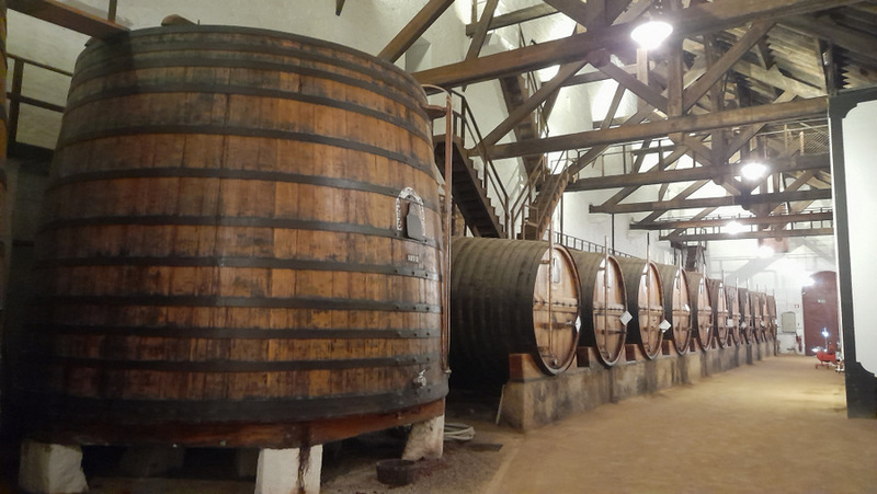 A large wooden barrel sits in a cozy room, complemented by a staircase, evoking the charm of Douro Valley tours.