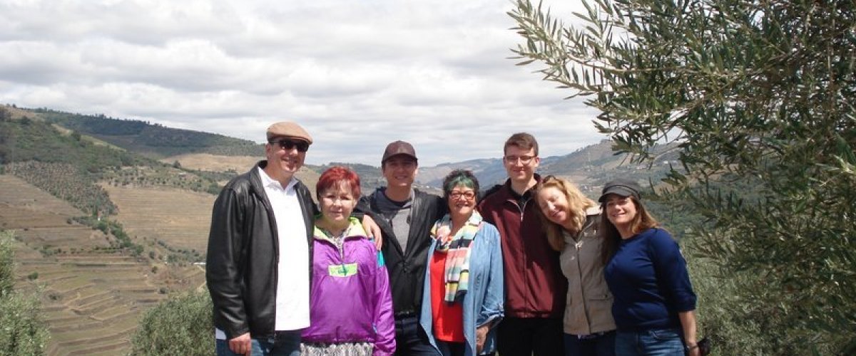 A joyful family group stands together, enjoying a scenic tour in the beautiful Douro Valley.