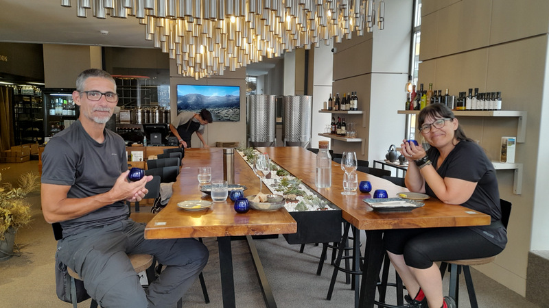 A couple savoring olive oil at a table, each holding a drink, immersed in a delightful tasting experience.