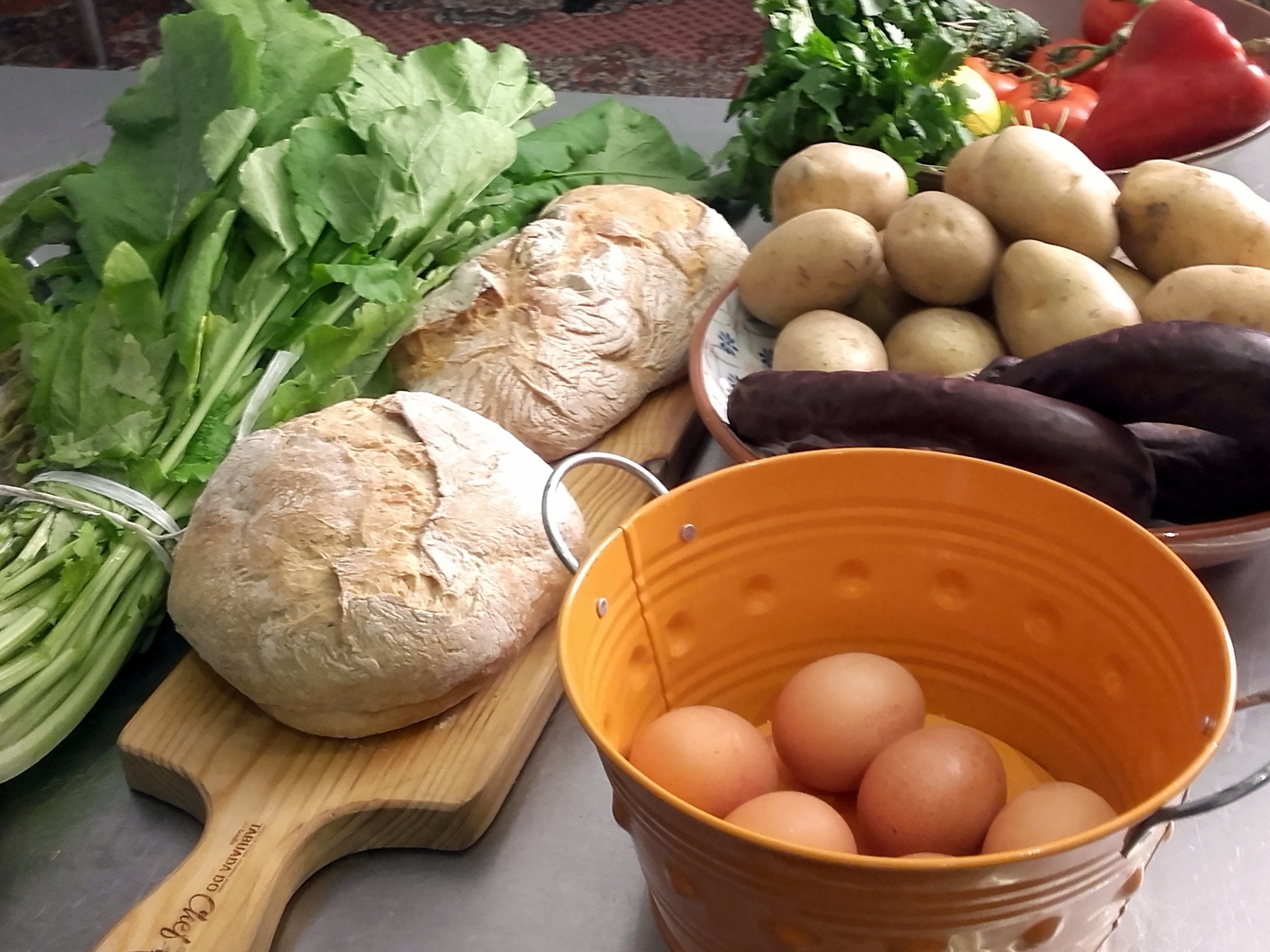A vibrant table filled with fresh vegetables and bread, set for a cooking class in Portugal, showcasing local culinary delights.