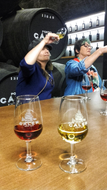 women enjoy wine tasting at a table in Porto, Portugal, each holding a glass and sharing laughter and conversation.
