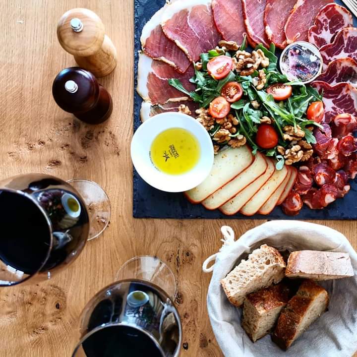 A delicious spread of smoked Portuguese sausages and colorful vegetables, paired with wine glasses, ideal for a culinary adventure.