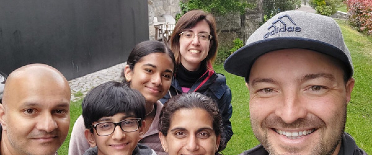 A cheerful group of tourists taking a selfie in front of a charming hotel during a Portugal wine and food tour.