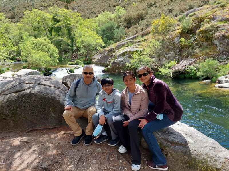 A cheerful family gathers on a scenic path by a river, soaking in the picturesque countryside of Portugal.