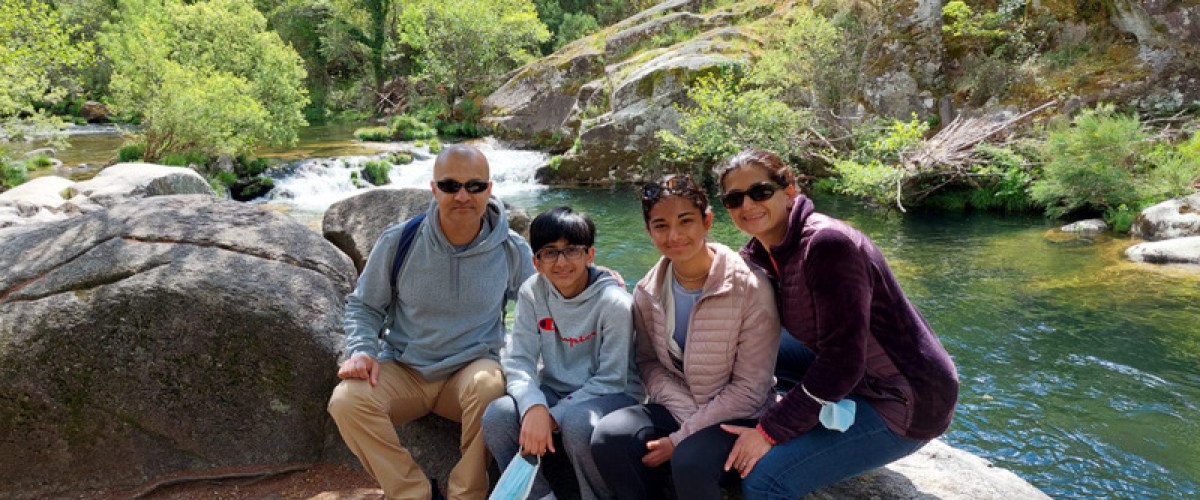 A cheerful family gathers on a scenic path by a river, soaking in the picturesque countryside of Portugal.