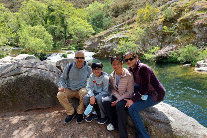 A cheerful family gathers on a scenic path by a river, soaking in the picturesque countryside of Portugal.