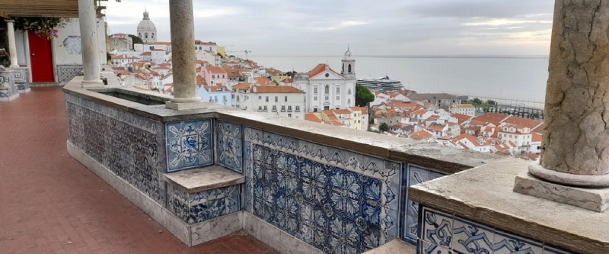 A charming balcony adorned with blue and white tiles, offering stunning views of Lisbon's vibrant cityscape.