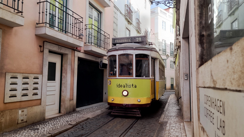 a yellow tram is parked in a narrow street in lisbon