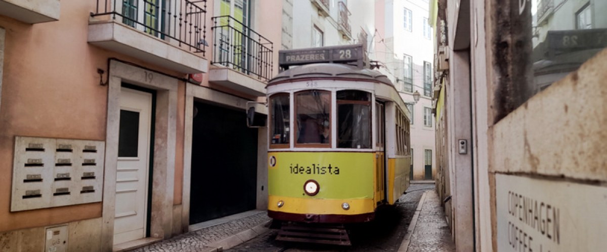 a yellow tram is parked in a narrow street in lisbon