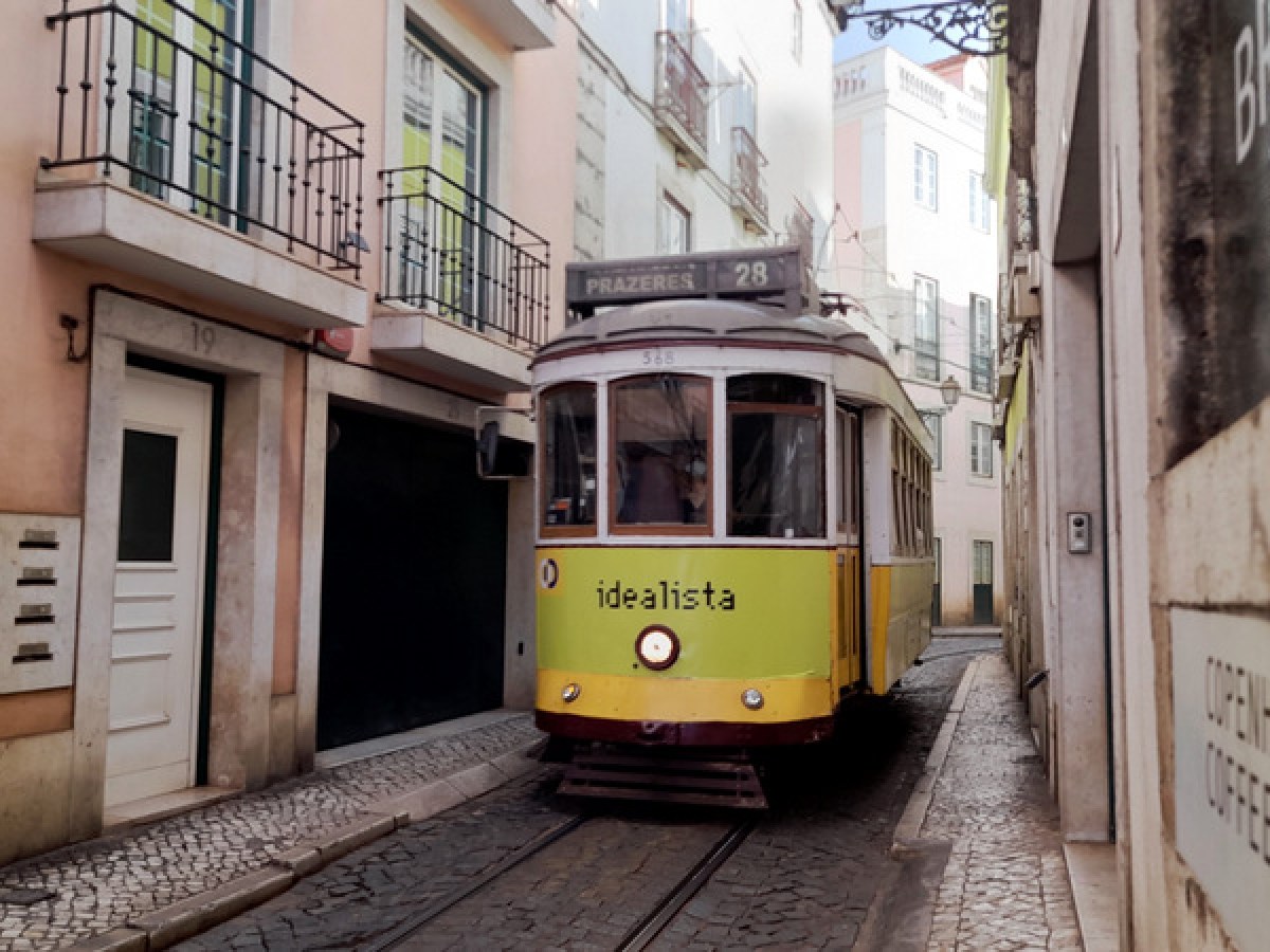 a yellow tram is parked in a narrow street in lisbon
