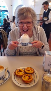 a person sitting at a table eating pastel belem