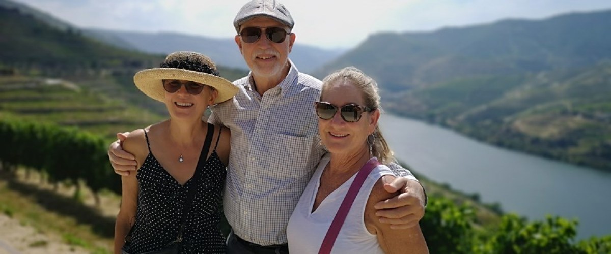 Three friends pose happily for a photo on a hillside during their hike in the beautiful Douro Valley.
