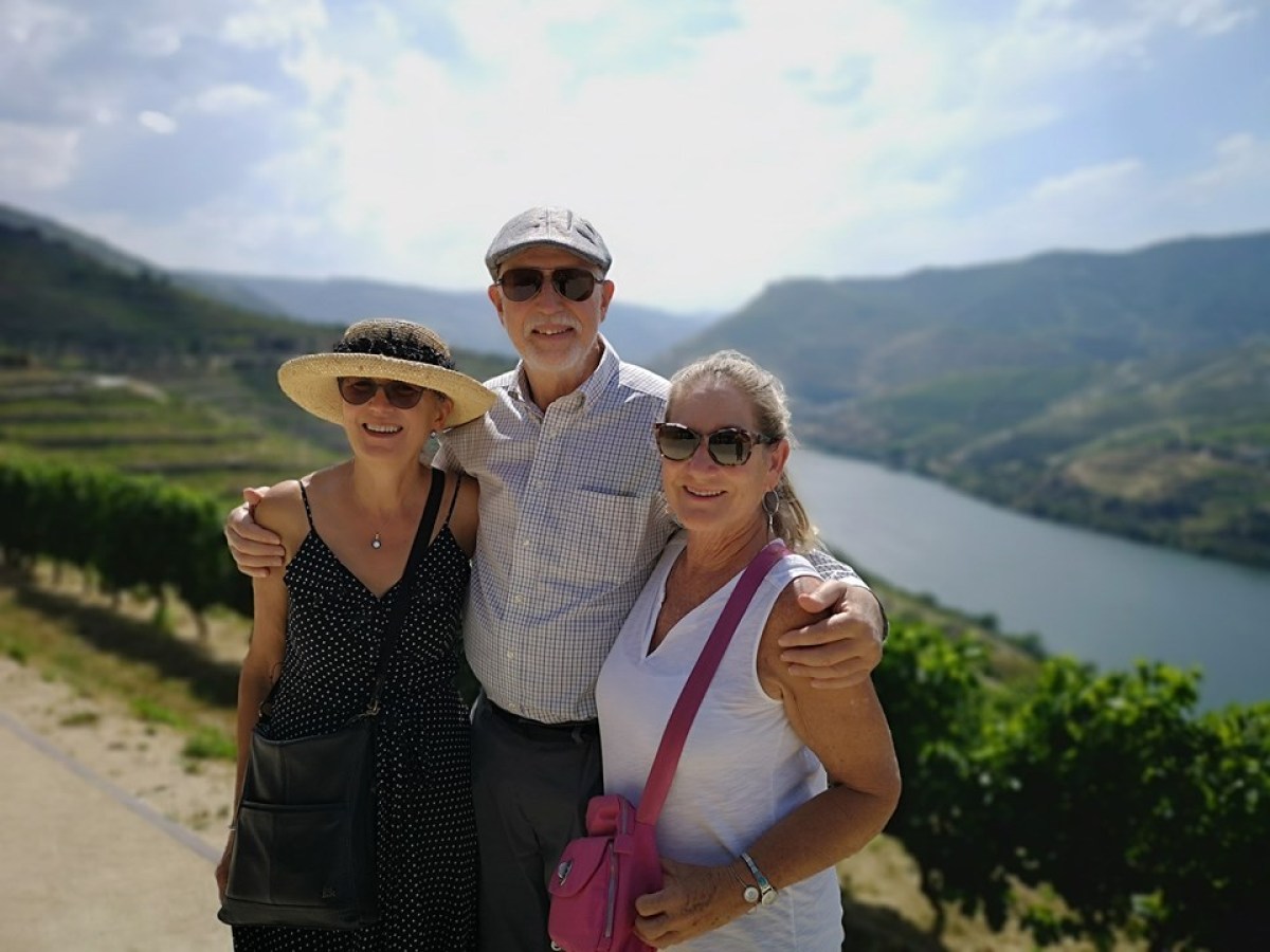 Three friends pose happily for a photo on a hillside during their hike in the beautiful Douro Valley.